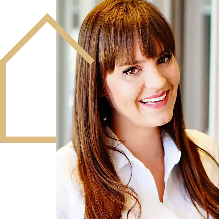 A woman with long brown hair and bangs, wearing a white collared shirt, smiles at the camera. A tan house-shaped outline is partially visible on the left side of the image.